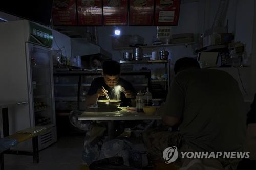 휴대전화 불빛으로 식사하는 중국 식당[AP=연합뉴스 자료사진]